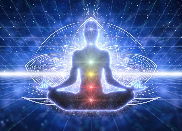 alt= "Figure of a person meditating and showing the chakras"